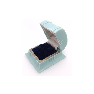 May include: A light blue ring box with a velvet interior. The box is open and the lid is propped up.