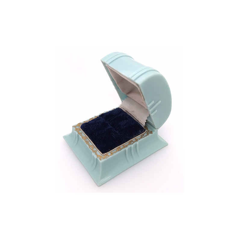 May include: A light blue ring box with a velvet interior. The box is open and the lid is propped up.
