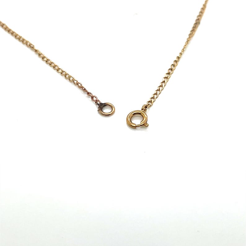 May include: A gold-colored necklace chain with a lobster clasp and a small ring on the other end. The chain is made of small, connected links. The background is white.
