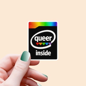 Könnte beinhalten: Ein quadratischer Aufkleber mit schwarzem Hintergrund und den Worten "queer inside" in Weiß. Das Wort "queer" befindet sich in einem weißen Oval, darunter farbige Herzen. Die Oberseite des Aufklebers hat ein Regenbogen-Design.