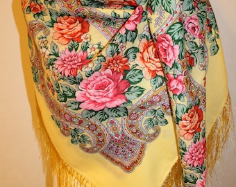 May include: A yellow silk scarf with a floral pattern and gold fringe. The scarf features a paisley design and a variety of flowers, including roses, daisies, and carnations.