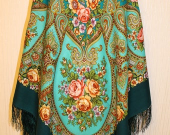 May include: A teal blue and dark green patterned shawl with floral designs and intricate details. The shawl has fringe on all sides.