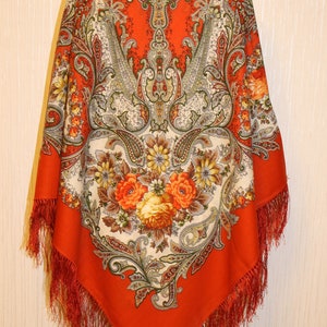 Może przedstawiać: Czerwony szal w wzór paisley z kwiatowym wzorem i frędzlami. Szal jest wykonany z jedwabiu i ma tradycyjny rosyjski wzór.