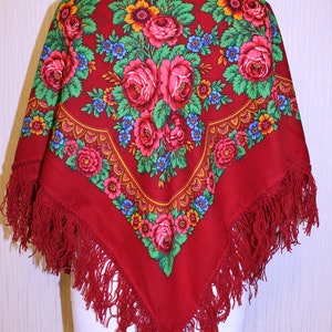 以下が含まれることがあります： フリンジが付いた赤いショールで、花柄が施されています。ショールには、ピンクのバラ、緑の葉、青い花がデザインされています。
