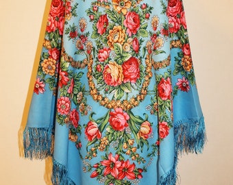 May include: A blue silk scarf with a floral pattern. The scarf has a fringe border and features a large bouquet of red, yellow, and pink flowers.