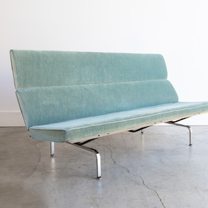 May include: A light blue mid-century modern sofa with a chrome frame and four legs. The sofa has a tufted back and seat cushions.