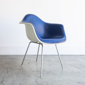 May include: A white and blue molded plastic chair with a chrome frame. The chair has a curved back and a wide seat.