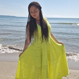May include: A bright yellow crochet dress with a flowing skirt and a sleeveless design. The dress is made with a delicate openwork pattern.