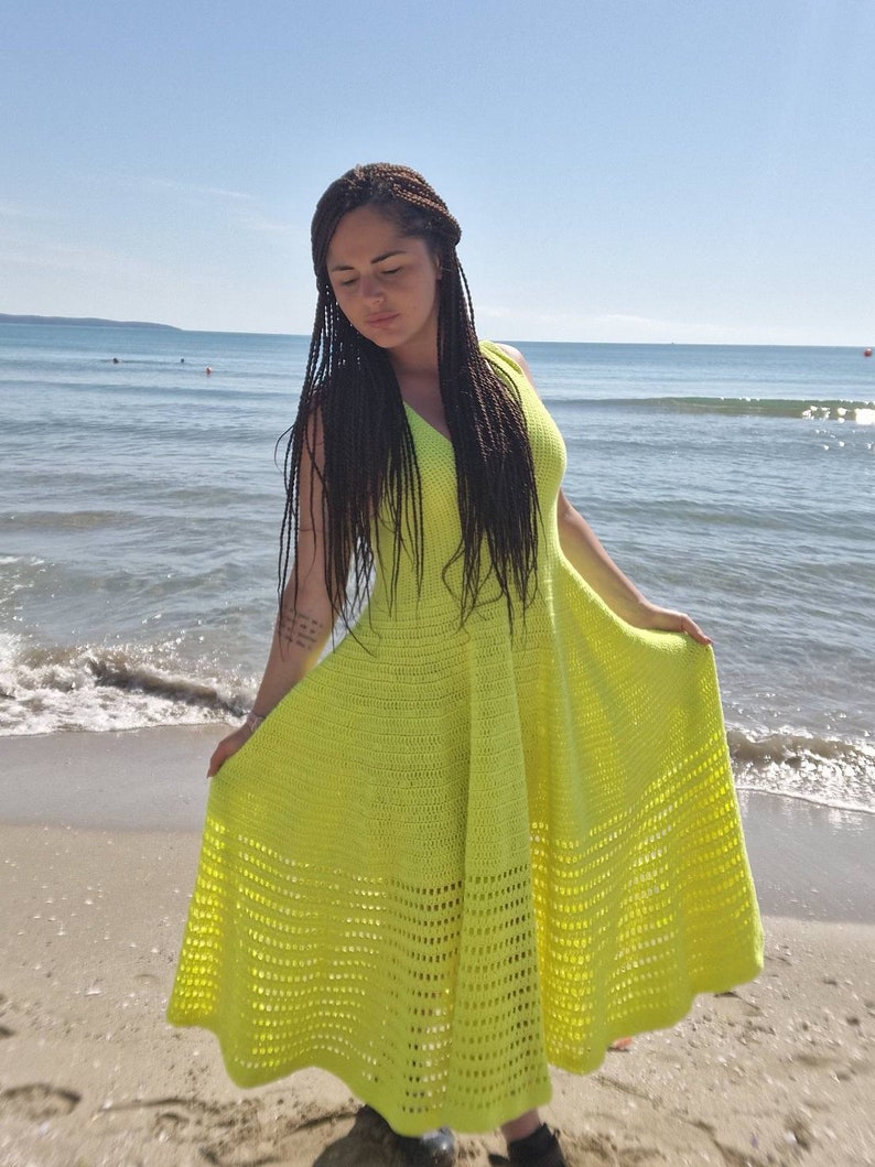 May include: A bright yellow crochet dress with a flowing skirt and a sleeveless design. The dress is made with a delicate openwork pattern.