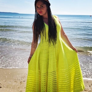 May include: A bright yellow crochet maxi dress with a V-neckline and a flowy skirt. The dress is made with a delicate openwork pattern.