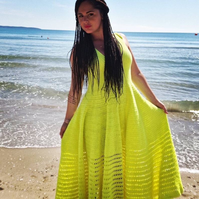 May include: A bright yellow crochet maxi dress with a V-neckline and a flowy skirt. The dress is made with a delicate openwork pattern.