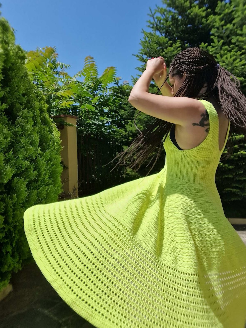 May include: A bright neon green crochet dress with a flared skirt and a sleeveless design.