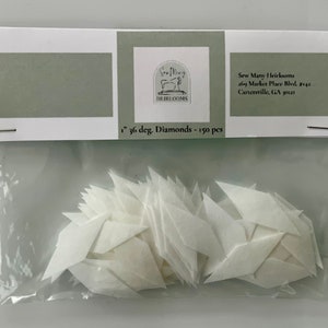 May include: A package of 150 white 1-inch 36-degree diamond-shaped fabric pieces. The package is labeled "Sew Many Heirlooms" and includes the address "209 Market Place Blvd. #142 Cartersville, GA 30121".