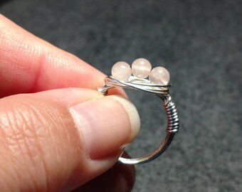 May include: A silver wire wrapped ring with three pink rose quartz beads.