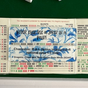 May include: A close-up of a game board with instructions for playing a game called "Charleston". The board is green and has a white border. The instructions are written in black and red text. The text includes the phrase "Never, ever use a joker in a pair!" and the words "Dragons: Crack-Red, Bam-Green, Dots-White (SOAP)".