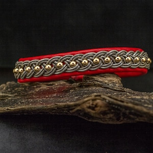 May include: A red leather bracelet with a silver and gold braided design and gold beads.