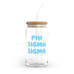 May include: A clear glass jar with a wooden lid and a glass straw. The jar has a blue and white design that says "PHI SIGMA SIGMA" with small yellow flowers.