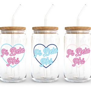 May include: Three glass jars with wooden lids and straws. Each jar has a heart-shaped design with the text "Pi Beta Phi" in a different color: pink, blue, and light blue.