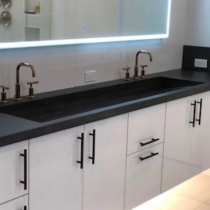 Concrete vanity top with integrated ramp sink and slot drain.