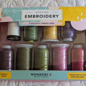 May include: An embroidery kit with a variety of colorful thread spools. The box reads "AMAZING EMBROIDERY" and "WONDERFUL SPECIALTY THREADS". Includes 9 spools and a thread hints and tips guide.