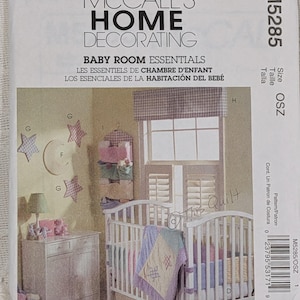 May include: A McCall's Home Decorating M5285 sewing pattern envelope for baby room essentials. The cover features a white crib with a pastel quilt, a white dresser, star-shaped wall decor, a hanging organizer, and a window with a valance.