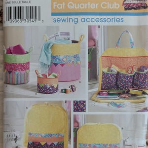 May include: Simplicity sewing pattern featuring various sewing accessories. The image showcases fabric storage baskets, a sewing machine cover, and a sewing kit. The accessories are decorated with colorful patterned fabrics, including paisley and geometric designs.