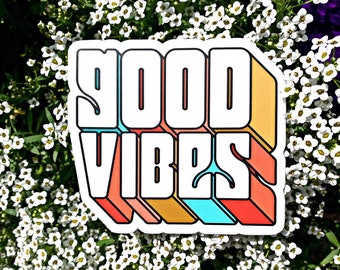 May include: A sticker with the words "GOOD VIBES" in a retro, colorful, 3D style. The letters are outlined in white and have a layered effect with shades of orange, yellow, blue, and red.