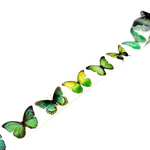 May include: A roll of washi tape with a repeating pattern of green, yellow, and blue butterflies. The butterflies are arranged in a line, with the largest butterfly at the end of the roll.