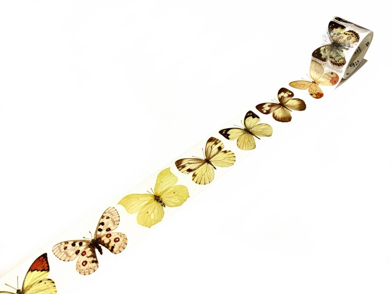 May include: A roll of washi tape featuring a line of yellow and brown butterflies. The tape is on a white background.
