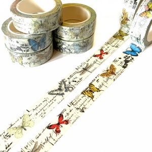 May include: Assortment of decorative washi tapes featuring a vintage aesthetic with butterflies, dragonflies, and handwritten script. The tapes are cream-coloured with brown, blue, red, and yellow accents.