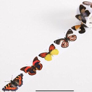 May include: A roll of washi tape featuring a repeating pattern of colorful butterflies. The butterflies are in various shades of red, orange, yellow, and black.