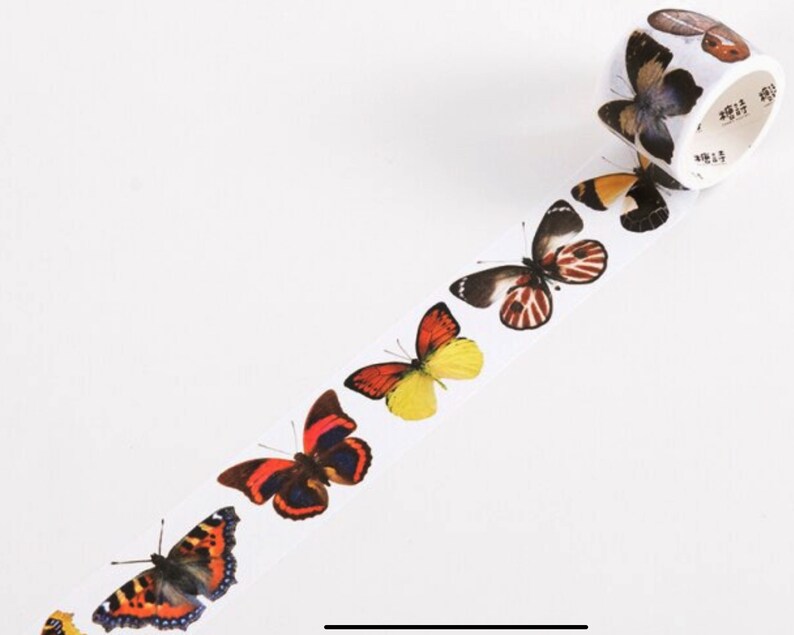 May include: A roll of washi tape featuring a repeating pattern of colorful butterflies. The butterflies are in various shades of red, orange, yellow, and black.