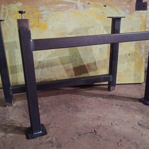 May include: A set of four black metal table legs with square bases. The legs are connected by two horizontal bars. The legs are about 30 inches tall.