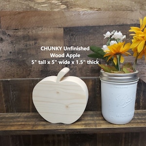 May include: Unfinished wooden apple shaped craft blank, 5 inches tall, 5 inches wide, and 1.5 inches thick.  The apple is sitting on a wooden shelf with a white painted mason jar filled with artificial flowers.