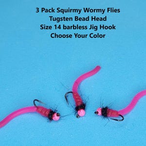May include: Three pink Squirmy Wormy Flies with black jig hooks and tungsten bead heads. The text on the image reads: "3 Pack Squirmy Wormy Flies, Tugsten Bead Head, Size 14 barbless Jig Hook, Choose Your Color."