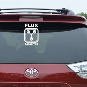 May include: A red car with a white vinyl sticker on the back window. The sticker says "Flux Capacitor" with a stylized image of a capacitor.