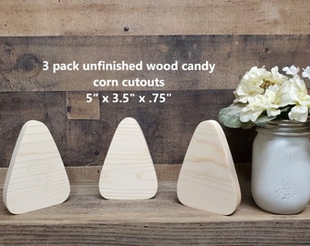May include: Three unfinished wooden candy corn cutouts, each measuring 5 inches by 3.5 inches by 0.75 inches. The cutouts are arranged in a row on a wooden surface.