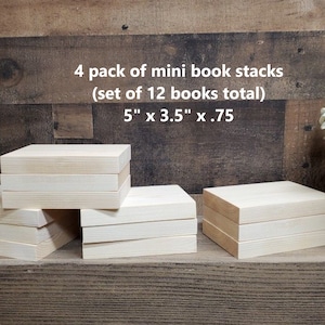 May include: Four stacks of unfinished wooden mini book blocks, each stack is 5 inches by 3.5 inches by .75 inches. The stacks are arranged on a wooden surface. The text "4 pack of mini book stacks (set of 12 books total) 5" x 3.5" x .75" is written above the stacks.