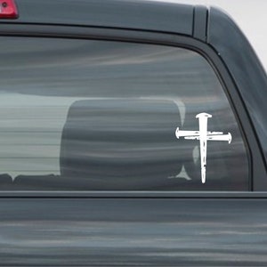 K&ouml;nnte beinhalten: Wei&szlig;er Vinyl-Aufkleber mit einem Kreuz mit N&auml;geln, geeignet f&uuml;r Autofenster oder andere glatte Oberfl&auml;chen.