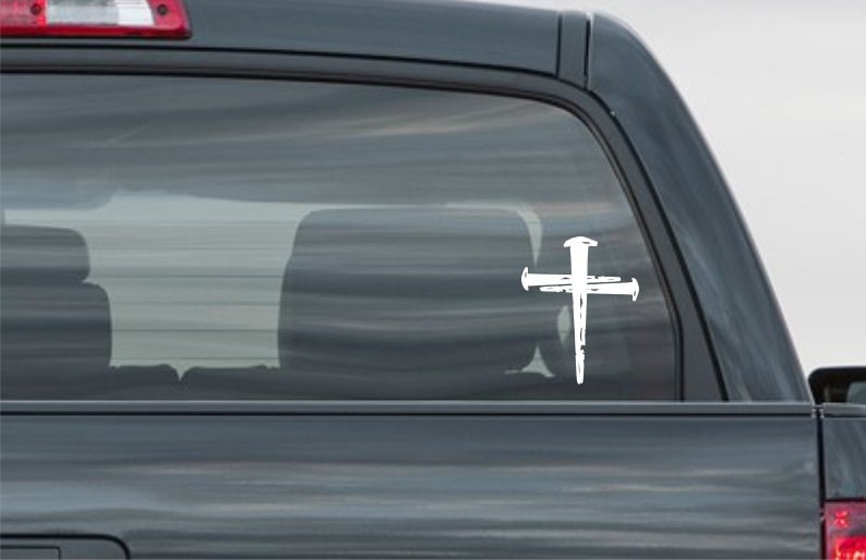 K&ouml;nnte beinhalten: Wei&szlig;er Vinyl-Aufkleber mit einem Kreuz mit N&auml;geln, geeignet f&uuml;r Autofenster oder andere glatte Oberfl&auml;chen.