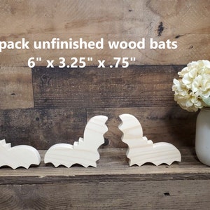 May include: Three unfinished wooden bats in the shape of bats. The bats are 6 inches long, 3.25 inches wide, and .75 inches thick.