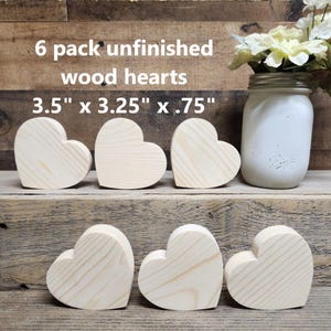 May include: Six unfinished wooden hearts in the shape of a heart. The hearts are 3.5 inches by 3.25 inches by .75 inches. The hearts are on a wooden surface.