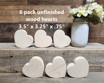 May include: Six unfinished wooden hearts in the shape of a heart. The hearts are 3.5 inches by 3.25 inches by .75 inches. The hearts are on a wooden surface.