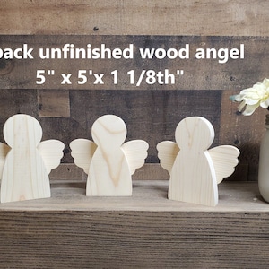 May include: Three unfinished wooden angel figurines, each measuring 5 inches by 5 inches by 1 1/8 inches. The angels are standing on a wooden surface.