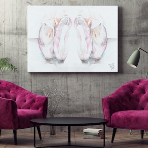 Puede incluir: Una pintura de acuarela de dos zapatillas de ballet rosas sobre un fondo blanco. La pintura está enmarcada y colgada en una pared gris sobre dos sillones de terciopelo rosa y una mesa de café negra.