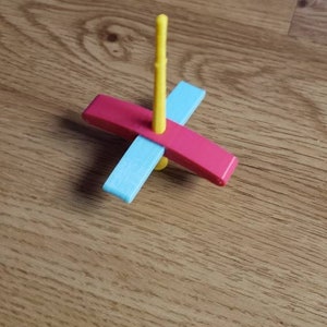 Peut inclure: Un jouet en plastique de couleur jaune, bleu et rose avec un design de toupie. Le jouet est simple et color&eacute;.