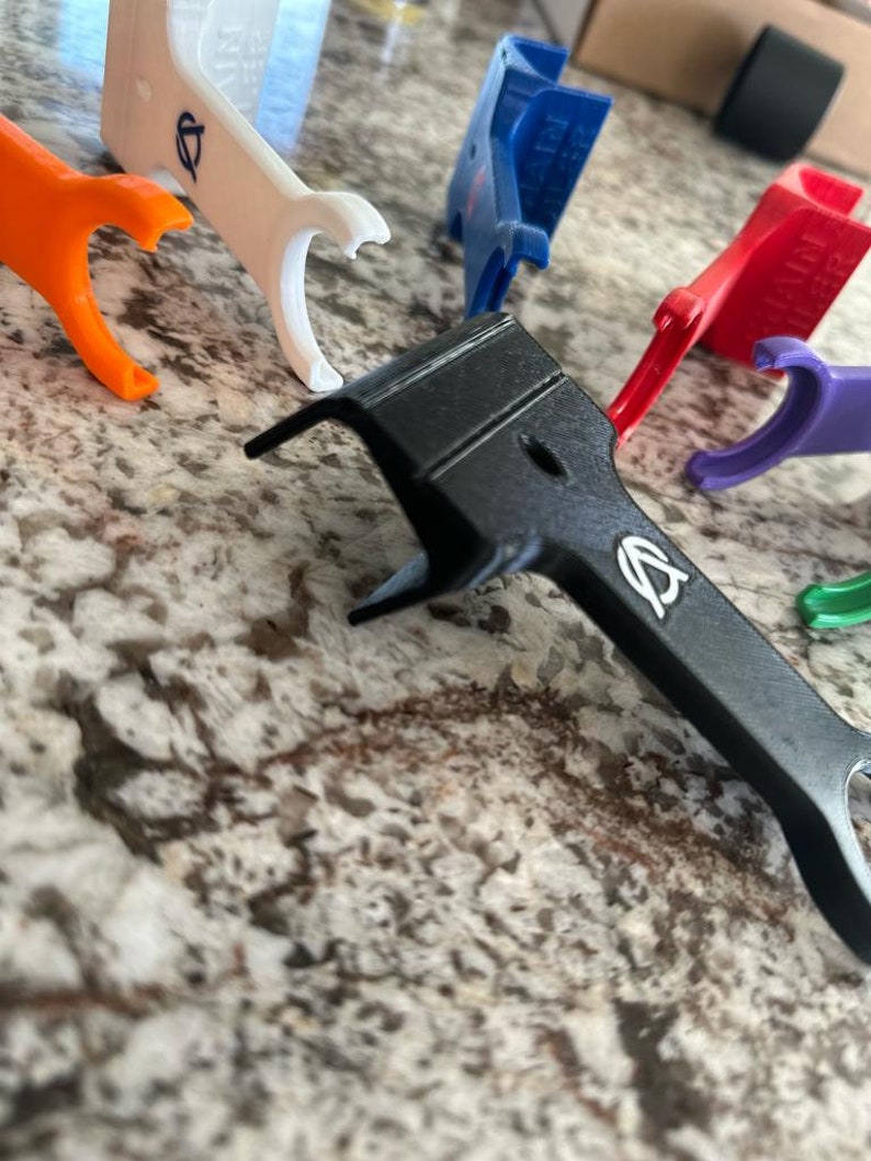 Pu&ograve; includere: Assortimento di pezzi in plastica stampati in 3D di vari colori con un logo. I pezzi sono di varie forme e dimensioni, tra cui un pezzo nero con un logo.