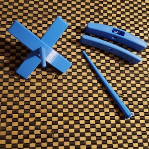Peut inclure: Un rouet bleu avec une broche et trois pi&egrave;ces suppl&eacute;mentaires. Le rouet est en plastique et a une base en forme de croix.