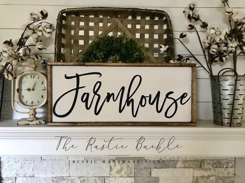 May include: A wooden sign with the word "Farmhouse" in black cursive script. The sign has a dark brown frame and a white background. The text "The Rustic Buckle" and "RUSTIC HANDMADE SIGNS" are also visible.