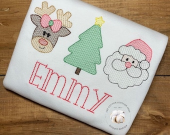 May include: A white embroidered Christmas-themed onesie with a reindeer, a Christmas tree, and Santa Claus. The onesie is personalized with the name "Emmy".